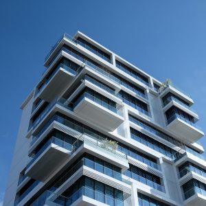Striking low-angle shot of a modern condominium with unique balcony design and clear blue sky.